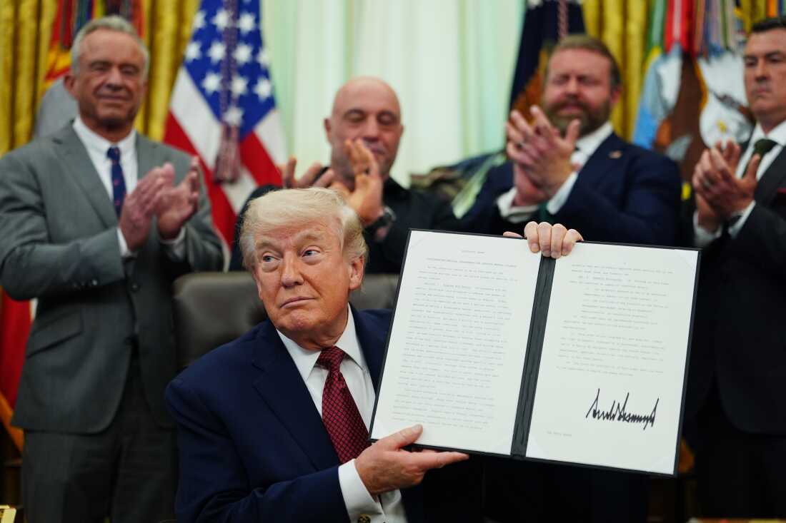 President Donald Trump holds up a signed executive order in the Oval Office of the White House Saturday, April in Washington. (AP Photo/Julia Demaree Nikhinson)