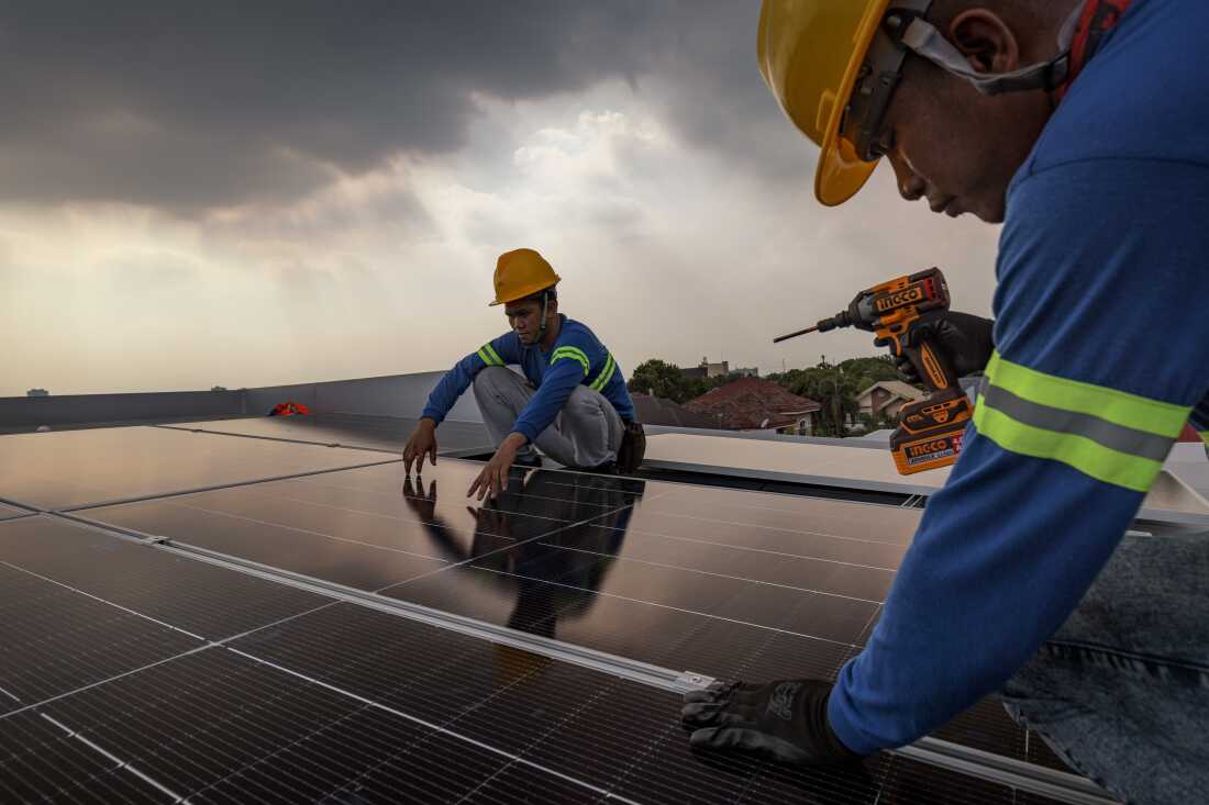 Workers install solar panels on the roof of a house on July 6, 2026 in Antipolo, Philippines.