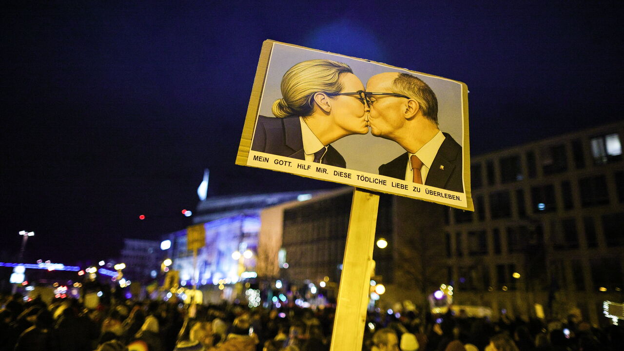 A demonstrator holds a banner with an AI image depicting Alice Weidel and Friedrich Merz kissing at an demonstration in Berlin